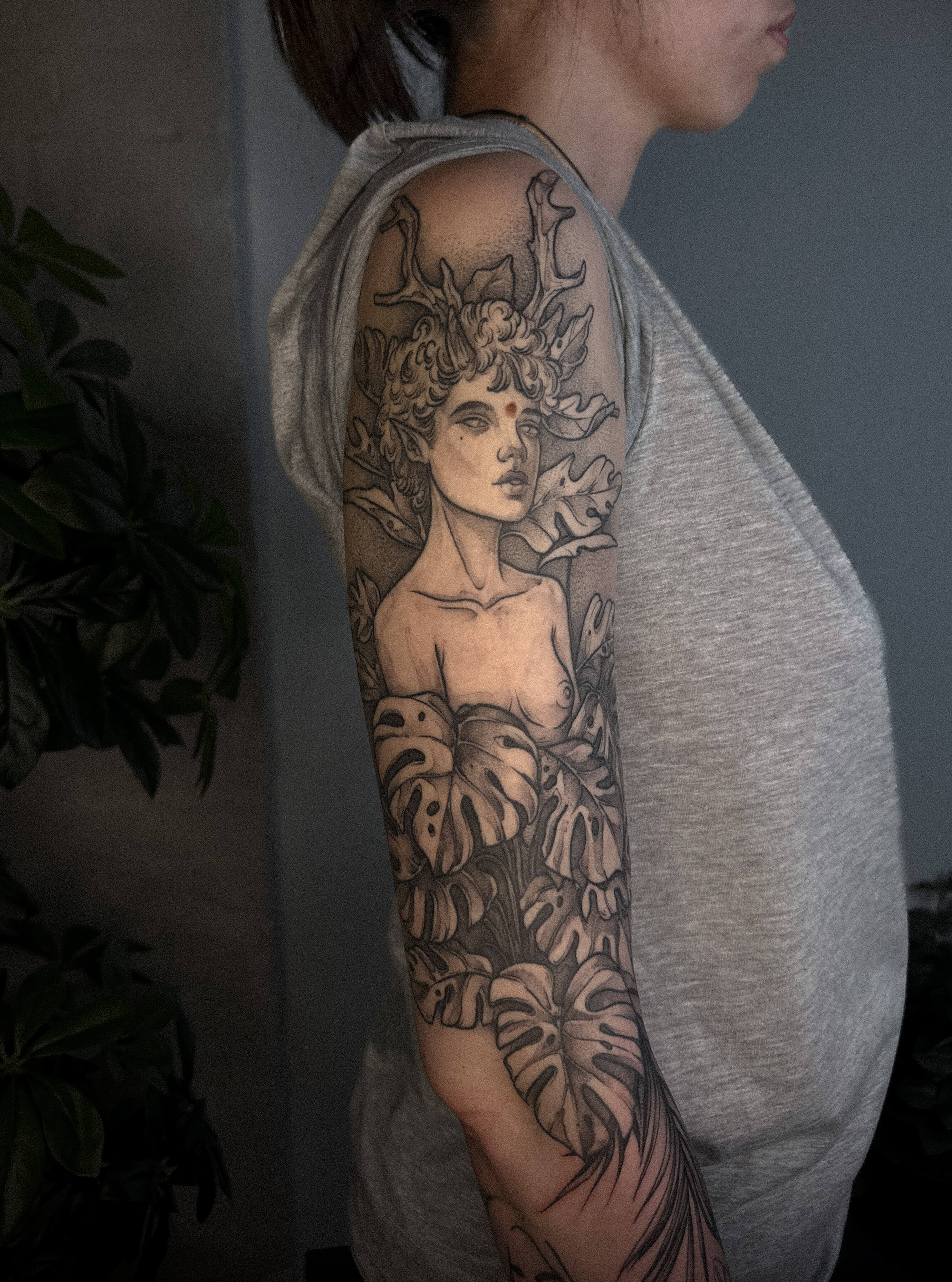 Full sleeve tattoo of nature goddess figure with antlers and monstera leaves — tattoo Barcelona